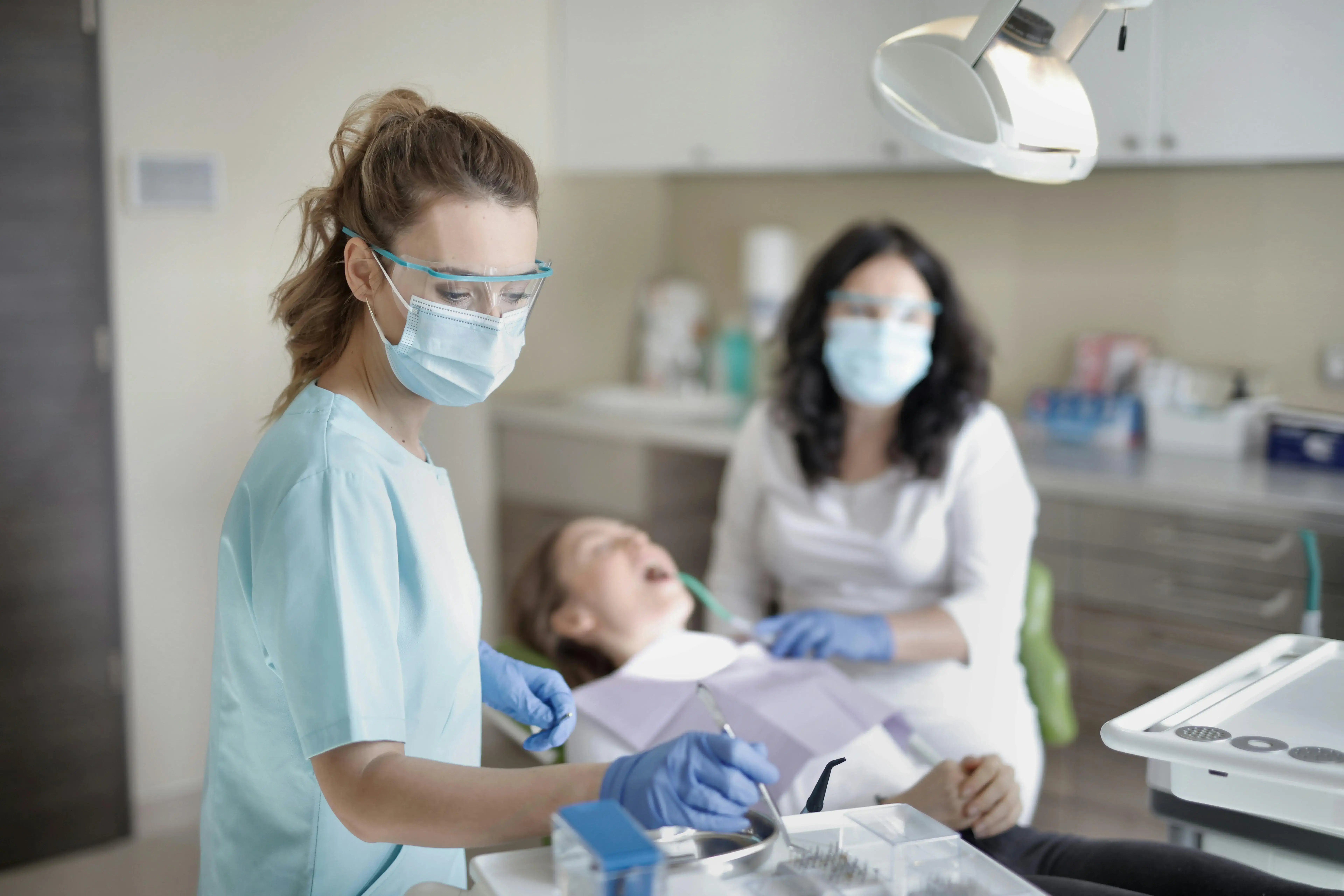 Dentist and nurse cleaning patient teeth