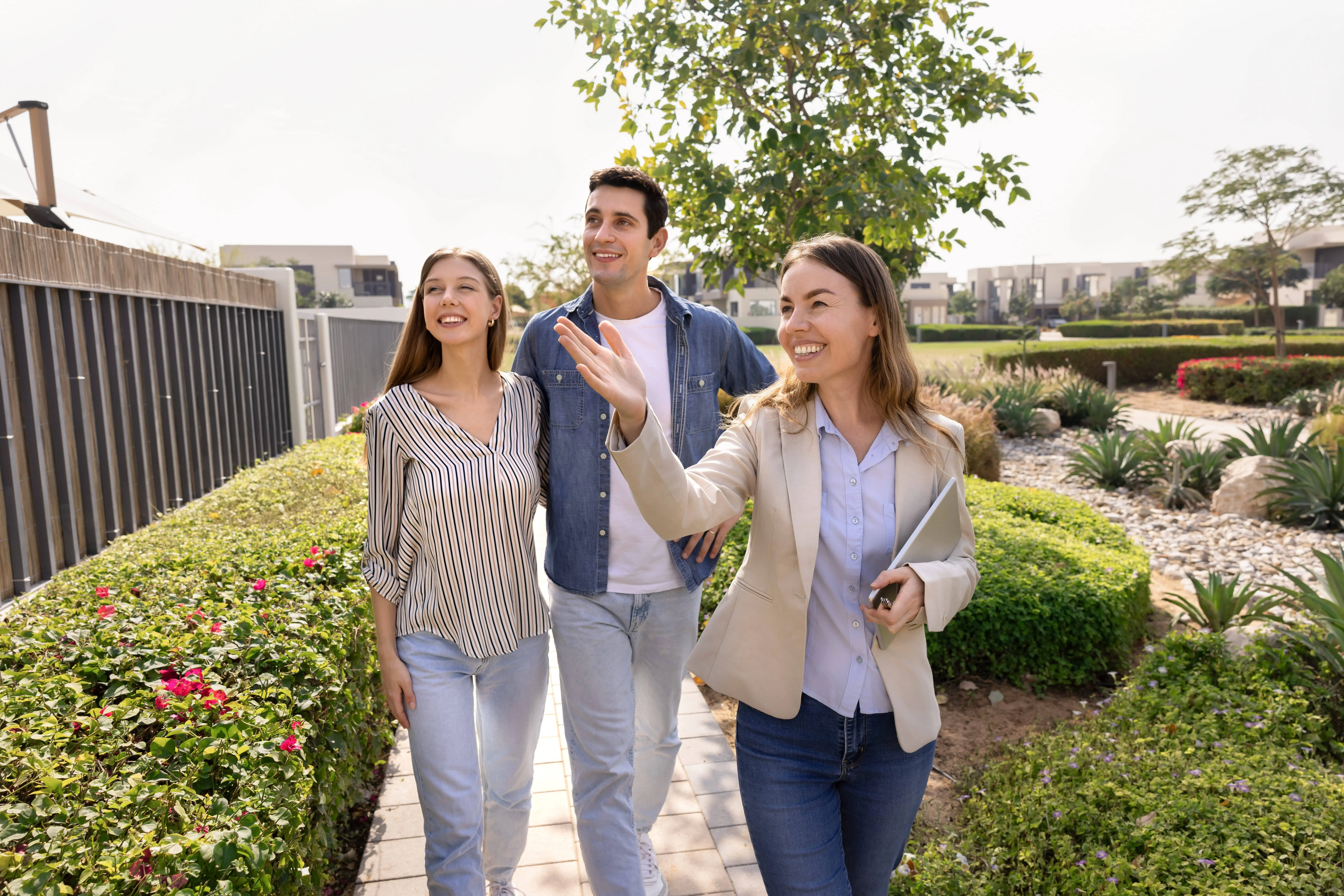 Real estate agent handing keys to happy clients in front of a new home